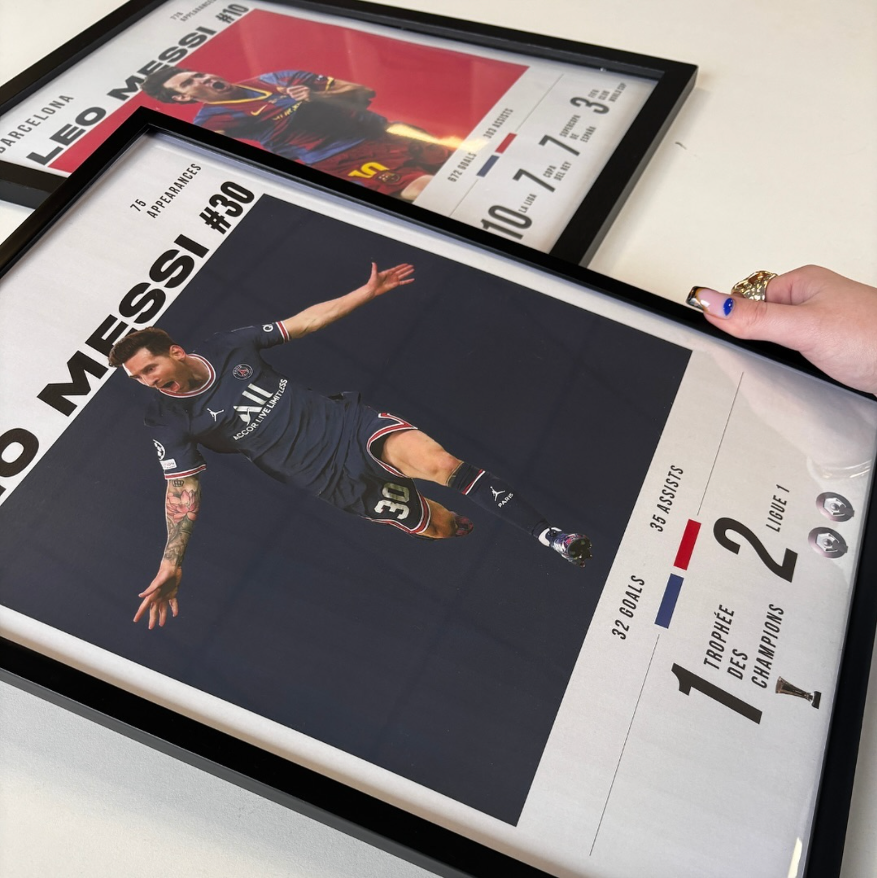 Hands holding two framed football kit art prints