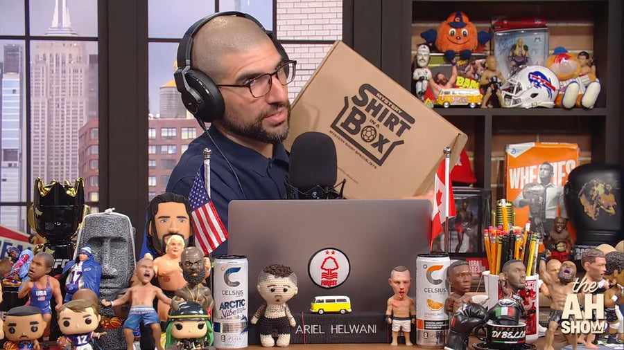 Ariel Helwani holding a Shirt in a Box mystery shirt box on The AH Show