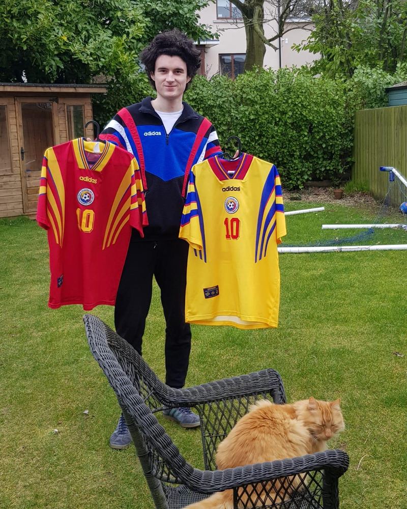 Rory in a garden holding two Romania shirts