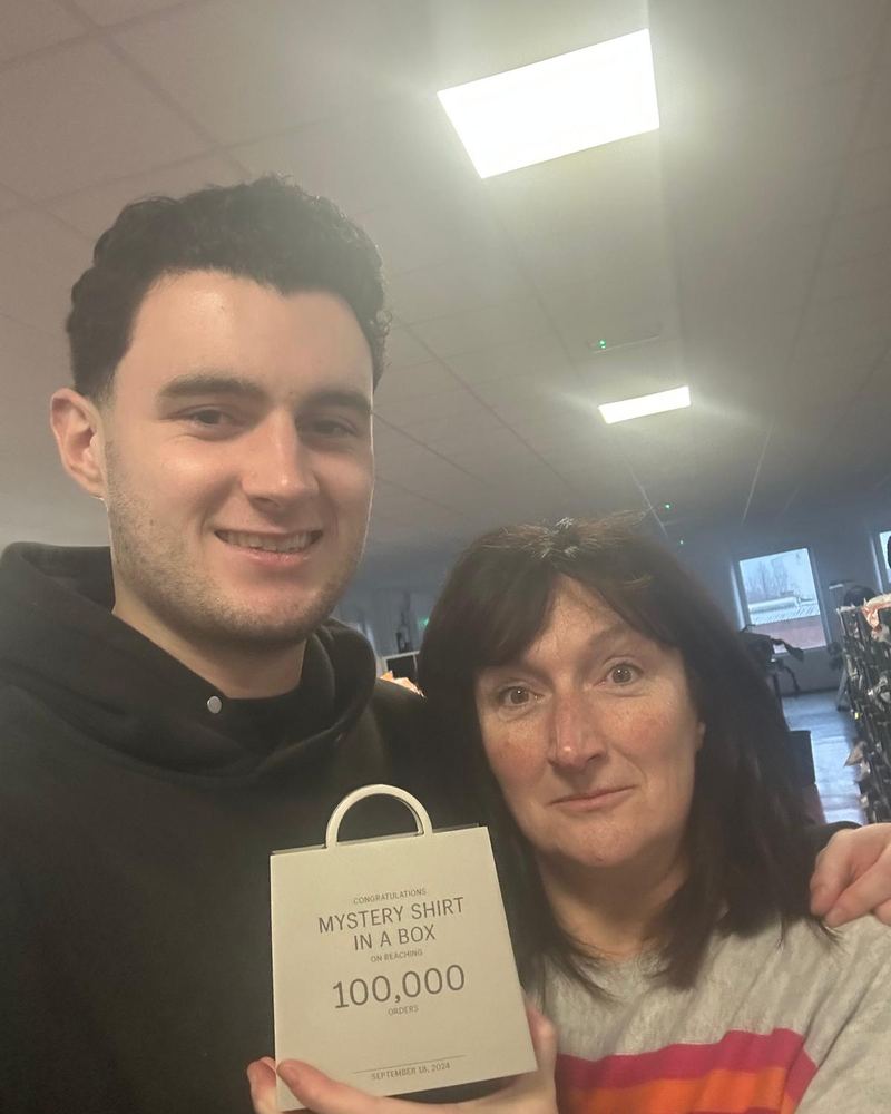 Rory and his mum holding a 100,000 orders plaque