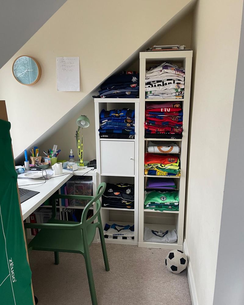 A bedroom desk and shelves full of shirts